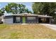 Charming single-story home featuring a well-maintained lawn and a covered carport with a bright green front door at 4311 W Oklahoma Ave, Tampa, FL 33616