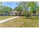 View of tan single Gathering home with green lawn, walkway, and mature trees on a sunny day at 4410 19Th N St, St Petersburg, FL 33714