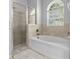 Spa-like bathroom showcasing a soaking tub, tiled shower, and arched window at 4809 Walnut Ridge Rd, Land O Lakes, FL 34638