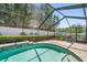 Backyard pool featuring an enclosure, landscaping, and a brick paver pool deck at 4868 Lake Valencia E Blvd, Palm Harbor, FL 34684