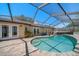 Exterior view of the screened in pool with landscaping and brick paver pool deck at 4868 Lake Valencia E Blvd, Palm Harbor, FL 34684