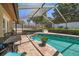 Inviting pool featuring a screened enclosure, lush landscaping, and brick paved deck at 4868 Lake Valencia E Blvd, Palm Harbor, FL 34684