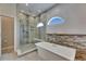 Modern bathroom showcasing freestanding tub, walk-in shower, half-moon window, and stone accent wall at 6301 Marbella Blvd, Apollo Beach, FL 33572