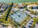 Aerial of community tennis courts, pool, and lush landscaping with ocean in background at 6301 Marbella Blvd, Apollo Beach, FL 33572