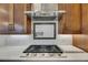 Close up of the gas cooktop with custom backsplash and stainless steel hood in the gourmet kitchen at 6301 Marbella Blvd, Apollo Beach, FL 33572