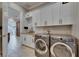 Well-equipped laundry room features modern appliances, cabinetry, butcher block counters, and tiled floors at 6301 Marbella Blvd, Apollo Beach, FL 33572
