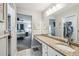 Bright bathroom featuring a granite countertop, white cabinets and an adjacent bedroom and walk-in closet at 6529 Thicket Trl, New Port Richey, FL 34653