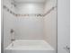 White bathtub with white tile backsplash and mosaic tile detail, features a showerhead and tub faucet at 805 E Elm St, Tampa, FL 33604