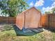 A backyard shed with a roll up door next to a tall, wooden fence at 8442 Pinewood Ave, Brooksville, FL 34613