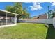 Large backyard featuring green grass, shade tree, and a screened-in patio, bordered by a privacy fence at 9504 Laurel Ledge Dr, Riverview, FL 33569