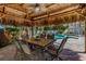 Thatched patio area with a dining table, perfect for outdoor meals near the pool at 102 Crestwood Ln, Largo, FL 33770