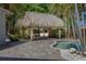 Charming outdoor dining area beneath a thatched roof, adjacent to a sparkling pool at 102 Crestwood Ln, Largo, FL 33770
