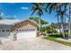 Attractive front exterior view showcasing a stone-accented home with a driveway, lush greenery, and a two-car garage at 102 Crestwood Ln, Largo, FL 33770