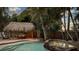 Relaxing pool and spa area with a charming tiki hut, surrounded by lush tropical landscaping at 102 Crestwood Ln, Largo, FL 33770