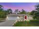 Inviting exterior showcasing a well-maintained lawn, a two-car garage, and a bright red front door at 10423 Sand Lark Ave, Weeki Wachee, FL 34614