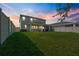 Spacious backyard with a covered patio, lush lawn, and privacy fence at sunset at 10814 Whitland Grove Dr, Riverview, FL 33578