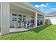 Covered patio with a table and chairs for outdoor dining, overlooking a well-manicured backyard at 10814 Whitland Grove Dr, Riverview, FL 33578