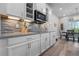 Well-lit kitchen with stainless microwave, white cabinets, mosaic backsplash, and adjacent dining area at 10814 Whitland Grove Dr, Riverview, FL 33578
