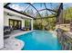 Beautiful screened-in pool area with a stone waterfall feature, surrounded by lush greenery at 11611 Meridian Point Dr, Tampa, FL 33626