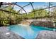 Backyard pool with waterfall feature, surrounded by a screened enclosure and mature trees at 11611 Meridian Point Dr, Tampa, FL 33626