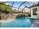 Inviting screened-in pool area with a custom stone waterfall feature and lush landscaping at 11611 Meridian Point Dr, Tampa, FL 33626