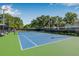 Community tennis court in blue and green with net and benches surrounded by trees and landscaping at 11611 Meridian Point Dr, Tampa, FL 33626