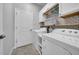 Bright laundry room featuring a white washer and dryer, white subway tile backsplash, and ample cabinet space at 11712 Winterset Cove Dr, Riverview, FL 33579