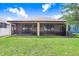 A covered and screened-in back porch sits at the edge of a well-maintained lawn on a sunny day at 1214 Florablu Dr, Seffner, FL 33584