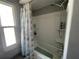 Bathroom showing tiled shower and tub with a seashell-patterned shower curtain and built-in shelving at 12432 81St Ct, Seminole, FL 33772