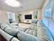Bright living room features a plush, wraparound sofa, modern lighting, and a stylish entertainment center at 12432 81St Ct, Seminole, FL 33772