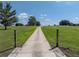 Long driveway leading to the property through sprawling green fields and mature trees under a bright blue sky at 1292 Myers Rd, Brooksville, FL 34602