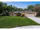 Well-maintained single-story home with lush front lawn, mature trees, and a two-car garage at 13806 Sumac Pl, Tampa, FL 33625