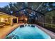 A screened-in pool with a brick deck, a seating area, and a view of the trees at 13806 Sumac Pl, Tampa, FL 33625