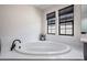 White bathroom featuring an oval tub with black faucet, and two windows with black frames at 14507 Woodland Spur Dr, Lithia, FL 33547