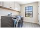 Well-lit laundry room featuring gray wood-look floors, modern appliances, and ample cabinet space at 14507 Woodland Spur Dr, Lithia, FL 33547