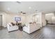 A living room featuring neutral sofas, a ceiling fan, tv, and gray hardwood floors at 14507 Woodland Spur Dr, Lithia, FL 33547
