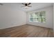 Bright bedroom with hardwood floors, ceiling fan and a large window overlooking a lush and tropical backyard at 16030 Bella Woods Dr, Tampa, FL 33647