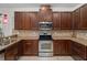Modern kitchen with stainless steel oven and microwave, warm granite countertops, and dark wood cabinetry at 16030 Bella Woods Dr, Tampa, FL 33647