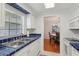 Bright kitchen with white cabinets, blue tile countertops, and stainless steel sink under the window at 1705 Belleair Forest Dr # B, Belleair, FL 33756