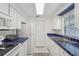 Well-lit kitchen featuring white appliances, white cabinetry, and blue tile countertop accents at 1705 Belleair Forest Dr # B, Belleair, FL 33756