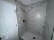 Bathroom shower with marble tile and white hexagon tile flooring at 1713 Valencia E Dr, Largo, FL 33778