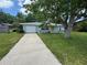 The exterior features a blue house with a yellow front door, a driveway, and mature trees at 1713 Valencia E Dr, Largo, FL 33778