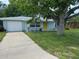 The exterior features a blue house with a yellow front door, a driveway, and mature trees at 1713 Valencia E Dr, Largo, FL 33778