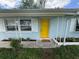 Close up of the yellow front door with white trim and a well-maintained lawn at 1713 Valencia E Dr, Largo, FL 33778