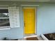 Close up of the yellow front door with white trim and a well-maintained lawn at 1713 Valencia E Dr, Largo, FL 33778