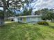 Charming single-story home with a well-maintained lawn, mature trees, and a bright yellow front door at 1713 Valencia E Dr, Largo, FL 33778
