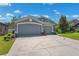 Charming gray home featuring a spacious three-car garage and well-maintained landscaping at 19750 Ellendale Dr, Land O Lakes, FL 34638