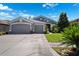Charming gray home featuring a spacious three-car garage and well-maintained landscaping at 19750 Ellendale Dr, Land O Lakes, FL 34638