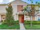 Inviting townhome facade with a vibrant red front door, manicured landscaping, and lush green lawn at 30340 Elderwood Dr, Wesley Chapel, FL 33543