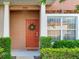 Welcoming townhome entrance with a vibrant red door, fresh green wreath, and manicured shrubbery at 30340 Elderwood Dr, Wesley Chapel, FL 33543